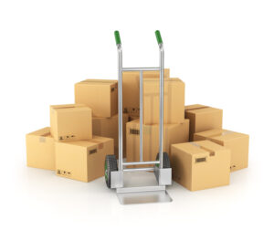 Piles of cardboard boxes with hand truck on white background.